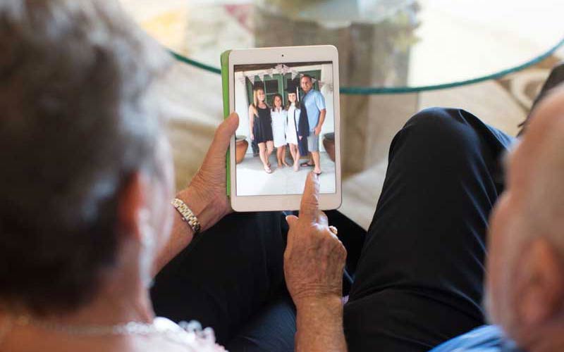 senior couple looking at tablet of family photos at memory care facility