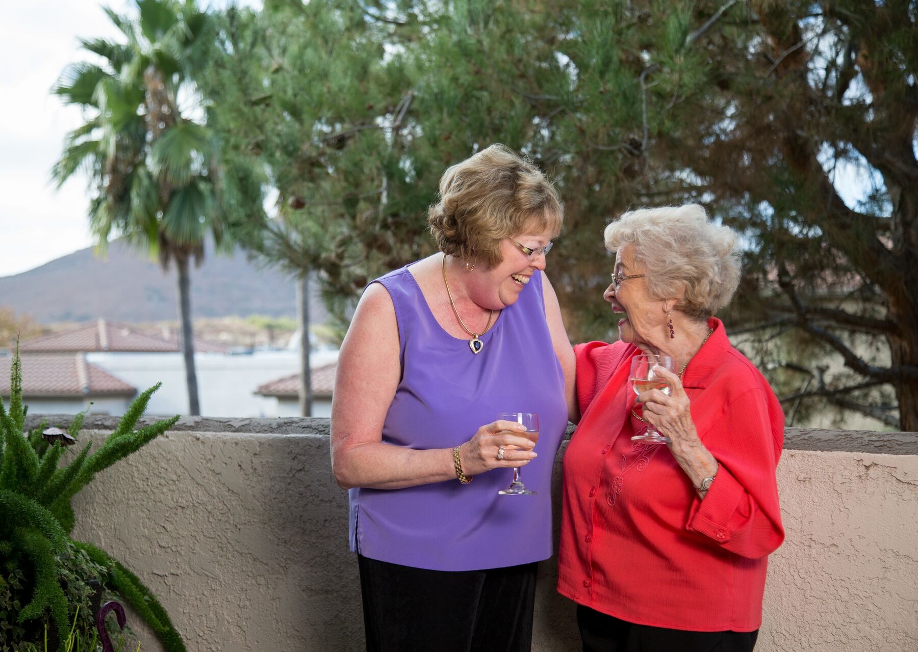 two senior women enjoying a drink on their patio apartment at a life plan community in San Diego