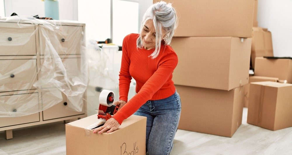 Senior woman packing boxes while downsizing her home.